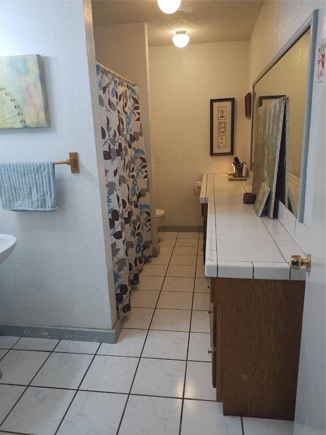 full bath featuring curtained shower, vanity, a textured ceiling, and toilet