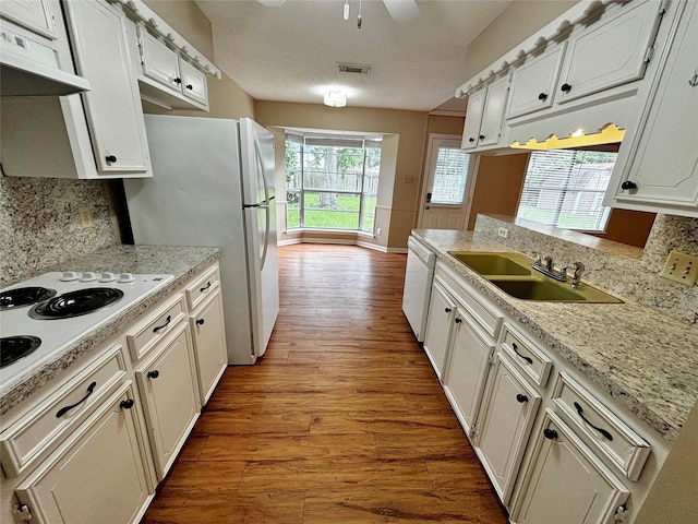 kitchen featuring sink, white cabinetry, tasteful backsplash, light hardwood / wood-style flooring, and white appliances