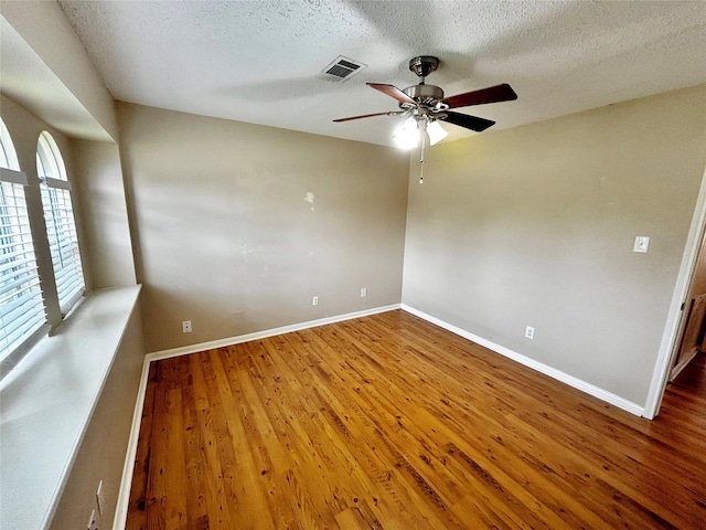 empty room with ceiling fan, hardwood / wood-style floors, and a textured ceiling