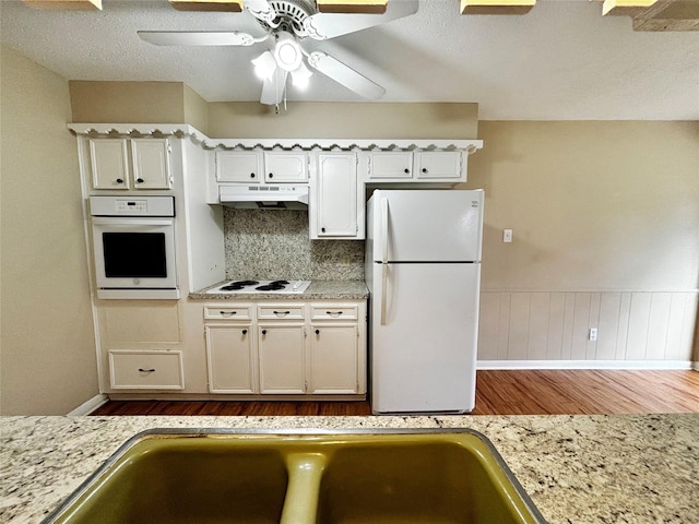 kitchen with white cabinetry, light hardwood / wood-style floors, white appliances, and decorative backsplash