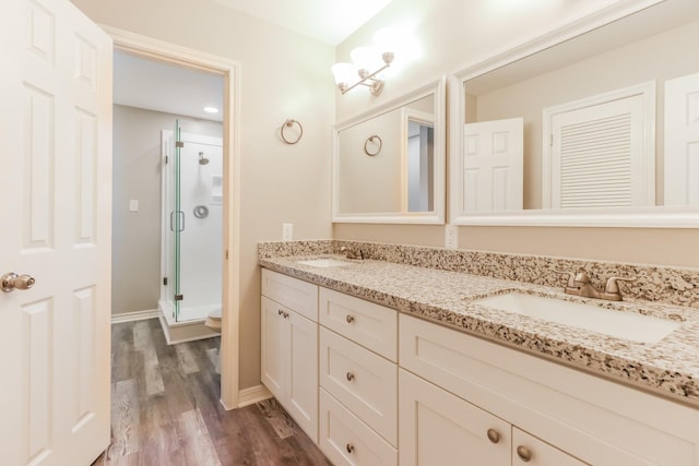 bathroom featuring toilet, vanity, a shower with door, and hardwood / wood-style floors