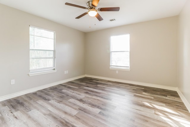 spare room featuring ceiling fan, a wealth of natural light, and hardwood / wood-style flooring