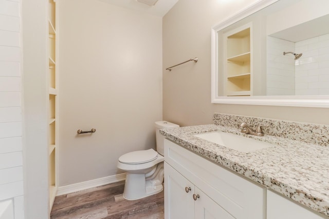 bathroom featuring toilet, vanity, tiled shower, hardwood / wood-style flooring, and built in features