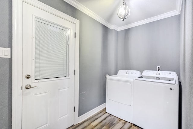 clothes washing area with crown molding, hardwood / wood-style flooring, and washing machine and clothes dryer