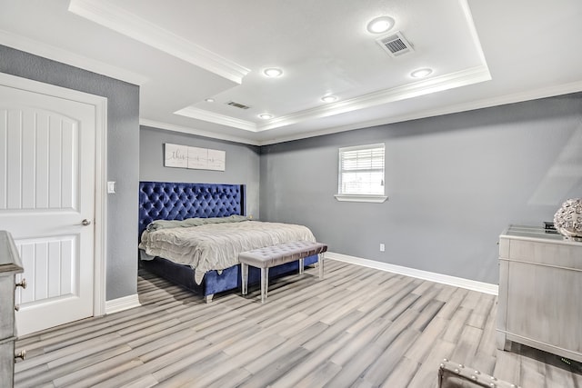 bedroom with light wood-type flooring, a raised ceiling, and ornamental molding