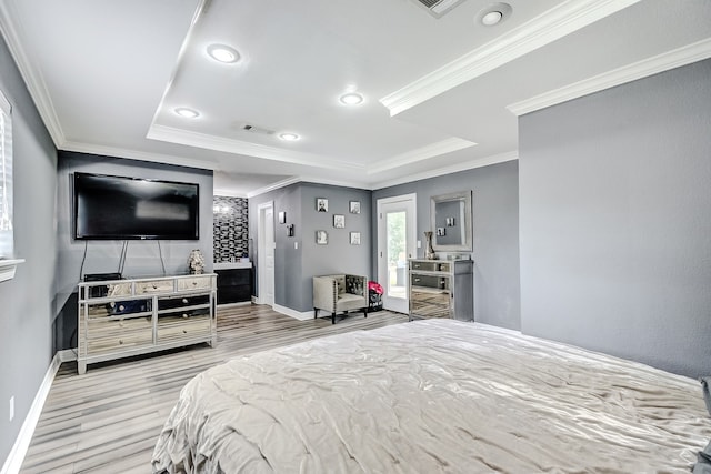 bedroom featuring ornamental molding, a tray ceiling, and light hardwood / wood-style floors