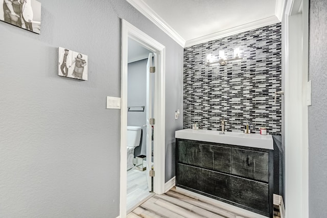 bathroom with vanity, toilet, ornamental molding, and hardwood / wood-style floors