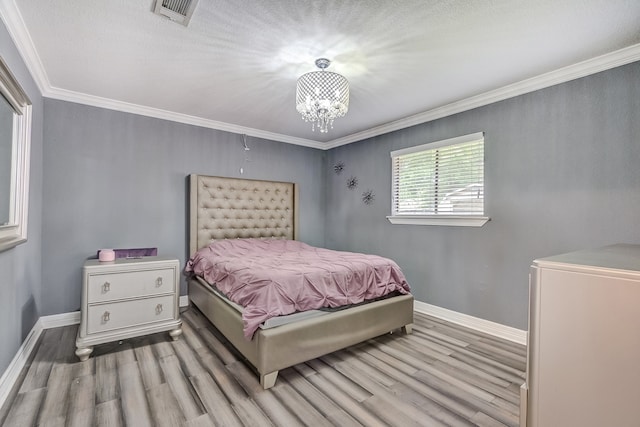 bedroom featuring ornamental molding, an inviting chandelier, and light wood-type flooring