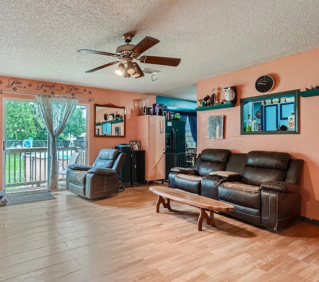 living room with light hardwood / wood-style flooring, a textured ceiling, and ceiling fan