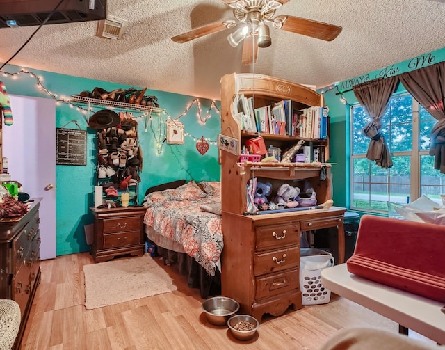 bedroom featuring ceiling fan, light hardwood / wood-style floors, and a textured ceiling