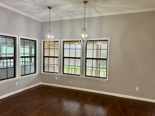 empty room featuring an inviting chandelier, crown molding, and dark wood-type flooring