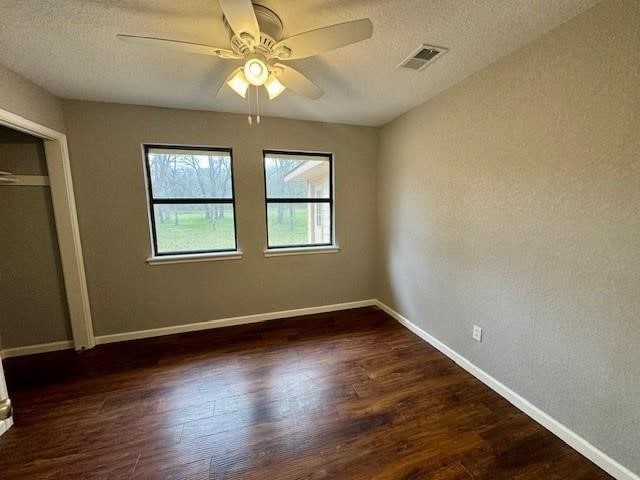 unfurnished bedroom featuring a closet, a textured ceiling, ceiling fan, and dark wood-type flooring