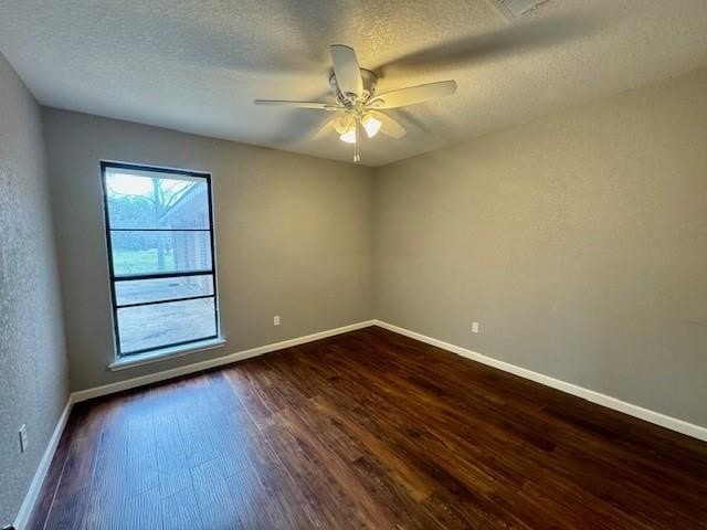 empty room with dark wood-type flooring, a textured ceiling, and ceiling fan