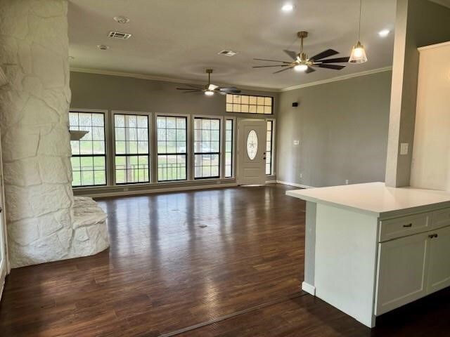 unfurnished living room with dark wood-type flooring, ceiling fan, and ornamental molding