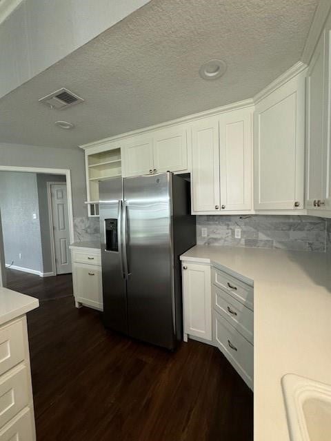 kitchen with stainless steel fridge, dark hardwood / wood-style flooring, white cabinetry, and decorative backsplash