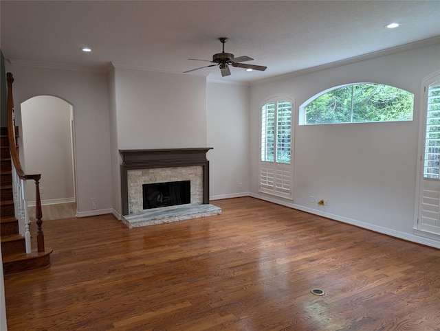 unfurnished living room with crown molding, dark hardwood / wood-style floors, ceiling fan, and a fireplace