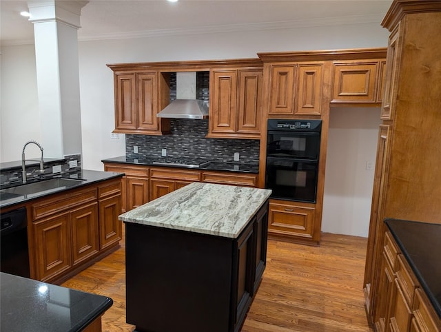 kitchen with wall chimney range hood, sink, hardwood / wood-style floors, a center island, and black appliances