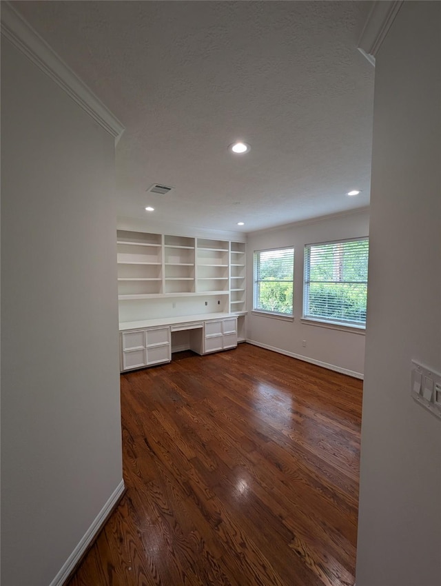 unfurnished living room with ornamental molding, dark hardwood / wood-style floors, built in desk, and a textured ceiling