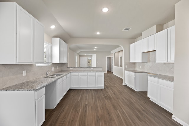 kitchen featuring white cabinets, sink, kitchen peninsula, backsplash, and dark hardwood / wood-style flooring