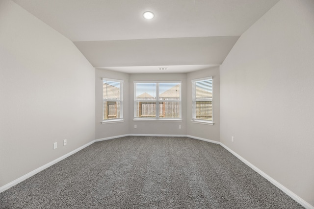 carpeted spare room featuring vaulted ceiling