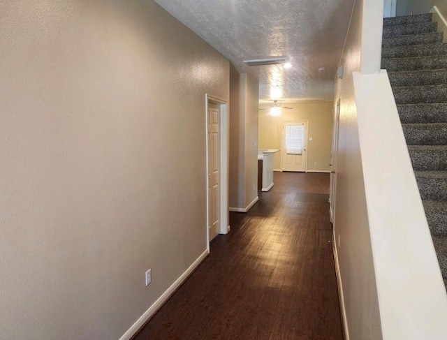 hallway with a textured ceiling and dark wood-type flooring