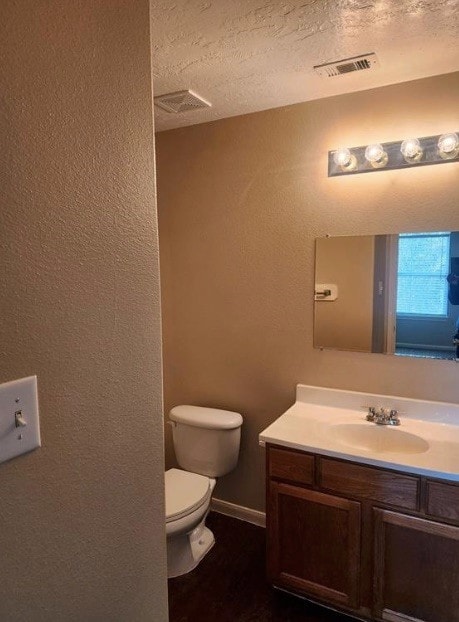 bathroom featuring toilet, vanity, and a textured ceiling