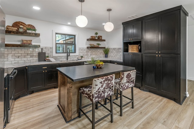 kitchen with tasteful backsplash, sink, a center island, a breakfast bar area, and light hardwood / wood-style floors