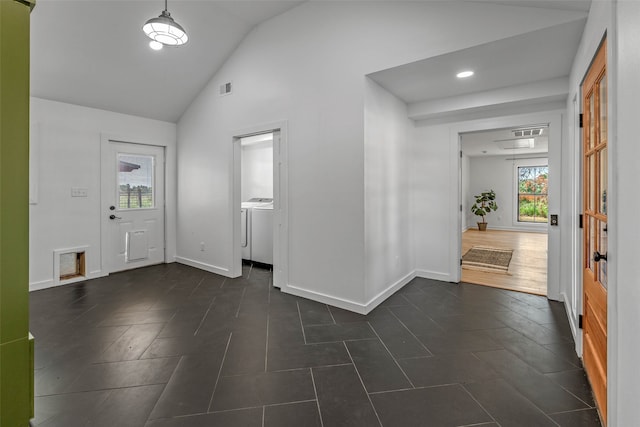 entryway with plenty of natural light, washing machine and clothes dryer, dark hardwood / wood-style floors, and vaulted ceiling