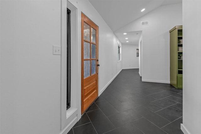 hall featuring lofted ceiling and dark tile patterned flooring