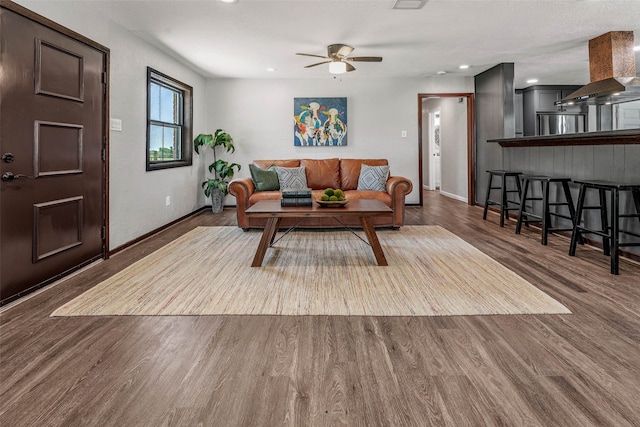 living room featuring ceiling fan and dark wood-type flooring