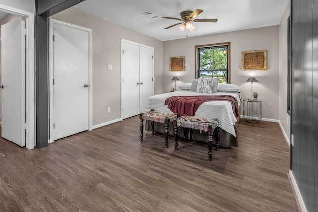 bedroom with multiple closets, dark wood-type flooring, and ceiling fan