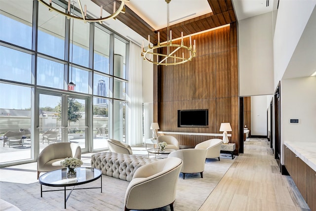 living room with light wood-type flooring, a high ceiling, and a chandelier