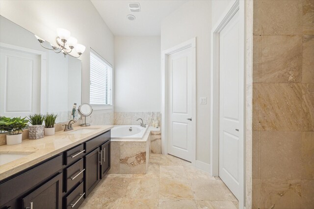 bathroom with tile patterned flooring, tiled bath, double sink vanity, and an inviting chandelier