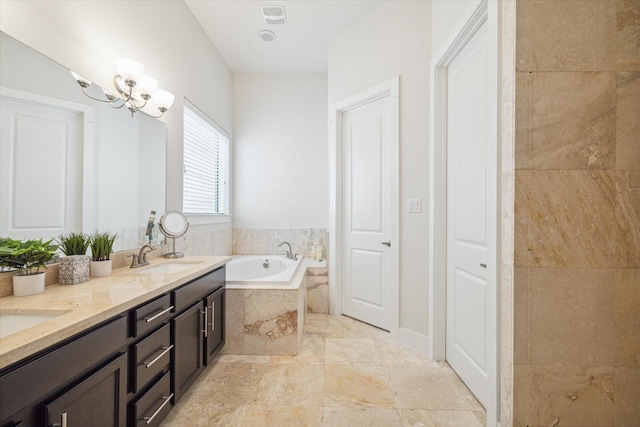 bathroom with tiled tub, vanity, and an inviting chandelier