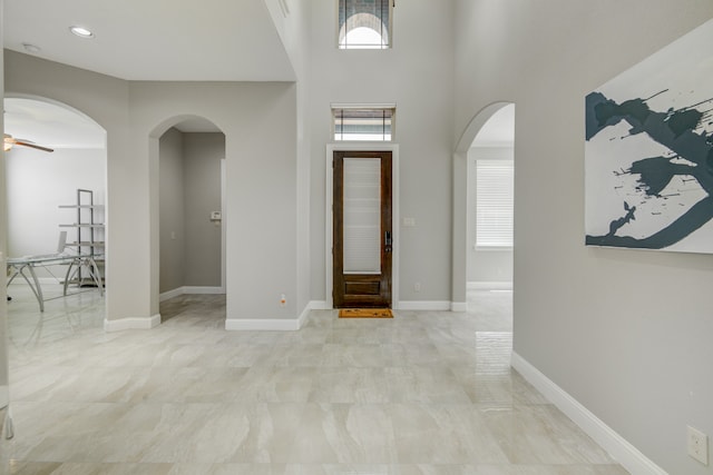 tiled entrance foyer featuring a towering ceiling and ceiling fan