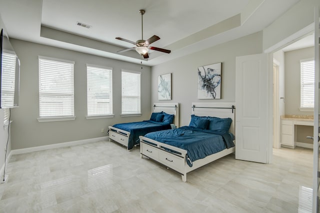 tiled bedroom featuring ceiling fan, ensuite bath, and a tray ceiling