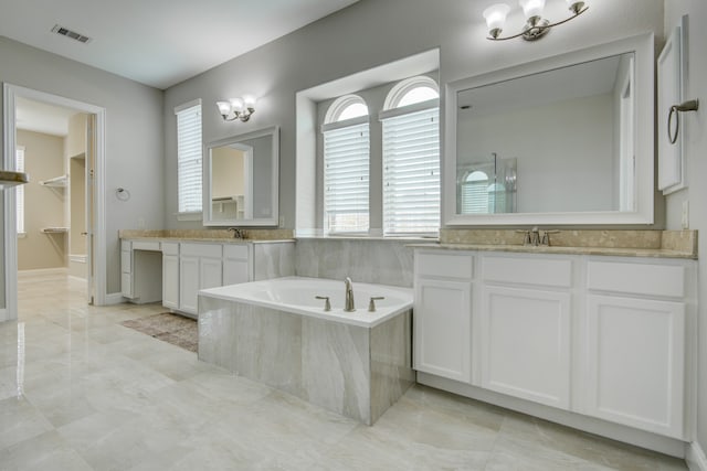 bathroom featuring tiled tub, vanity, an inviting chandelier, and tile patterned flooring