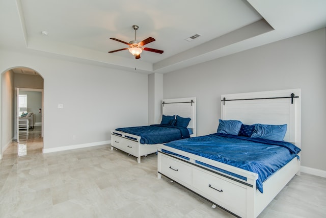 tiled bedroom with a raised ceiling and ceiling fan