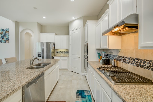 kitchen with white cabinetry, wall chimney range hood, sink, appliances with stainless steel finishes, and backsplash