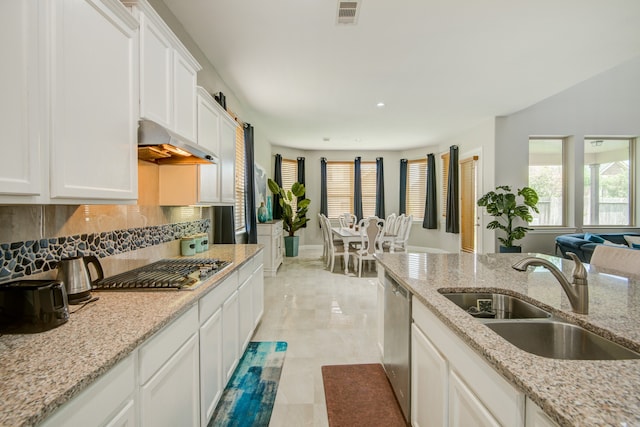 kitchen featuring stainless steel appliances, sink, backsplash, light tile patterned flooring, and wall chimney exhaust hood