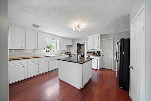 kitchen with electric stove, black fridge, white cabinets, and a kitchen island