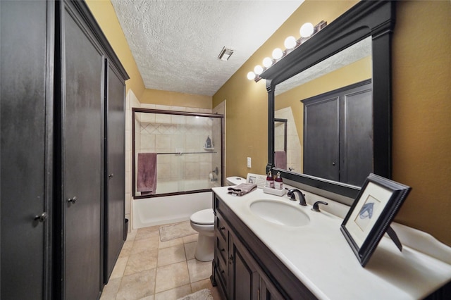 full bathroom featuring shower / bath combination with glass door, vanity, a textured ceiling, tile patterned floors, and toilet