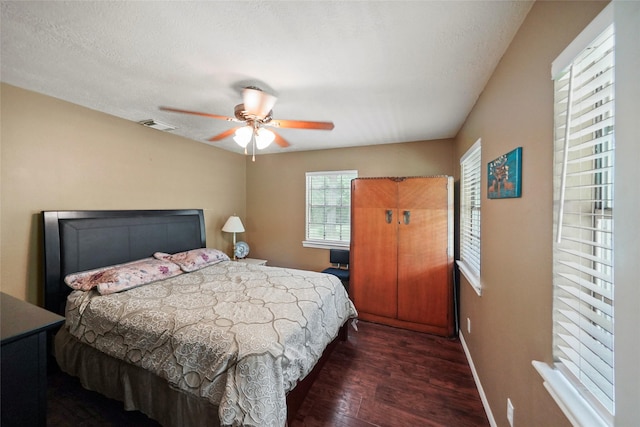 bedroom with ceiling fan, dark hardwood / wood-style floors, and a textured ceiling