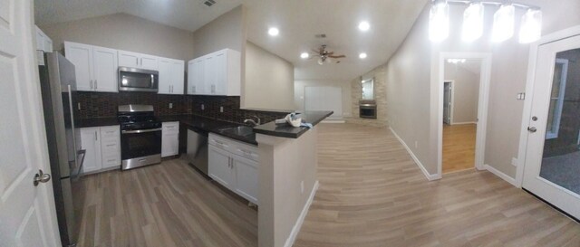 kitchen featuring appliances with stainless steel finishes, white cabinetry, wood-type flooring, and kitchen peninsula