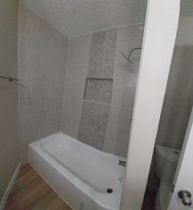 bathroom featuring tub / shower combination, hardwood / wood-style floors, toilet, and a textured ceiling