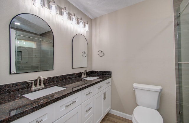 bathroom with a textured ceiling, toilet, walk in shower, and vanity