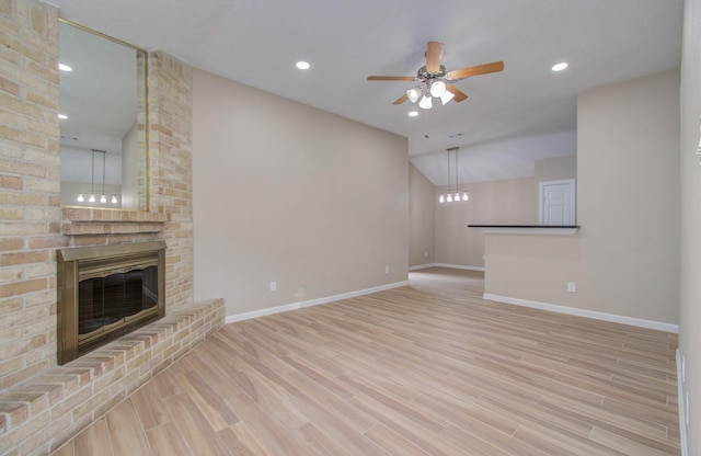 unfurnished living room featuring ceiling fan, light wood-type flooring, lofted ceiling, and a fireplace