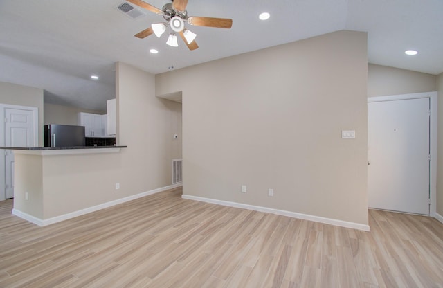 unfurnished living room featuring vaulted ceiling, ceiling fan, and light hardwood / wood-style flooring