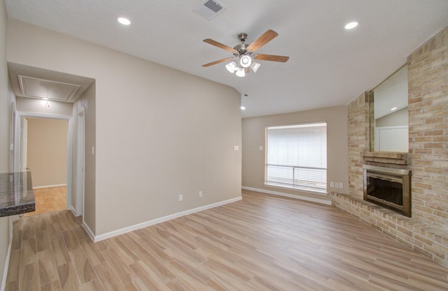 unfurnished living room with light wood-type flooring, ceiling fan, a brick fireplace, and vaulted ceiling