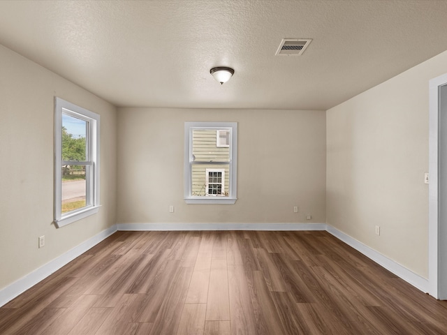 empty room with dark wood-type flooring and a textured ceiling